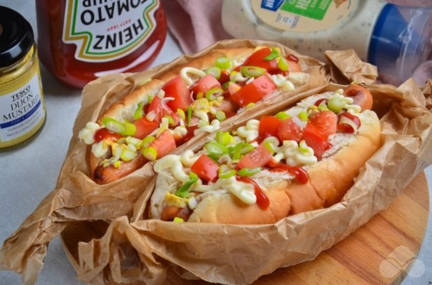 Homemade hot dog with fried sausage, tomatoes and green onions