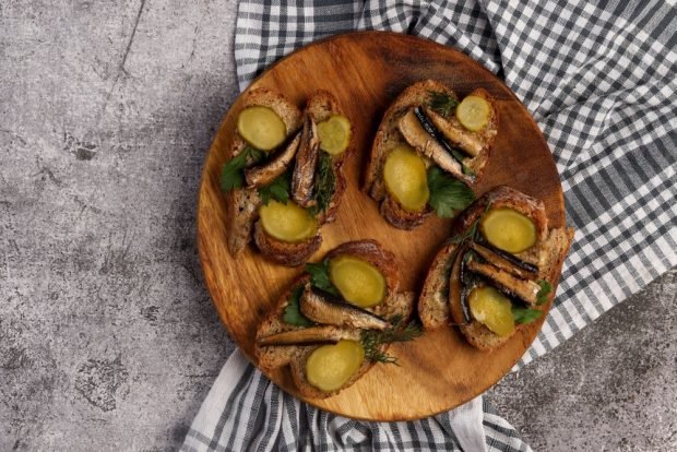 Sandwiches with sprats, garlic and cucumber on black bread