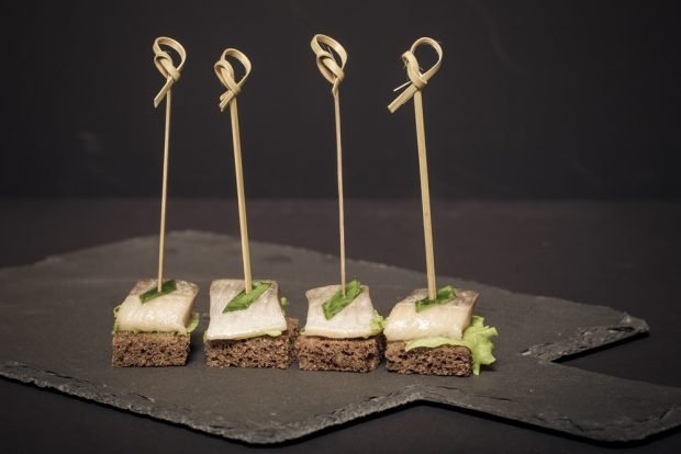 Canapé with herring on skewers and black bread