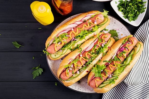 A hot dog with radishes, salad leaves and onions 