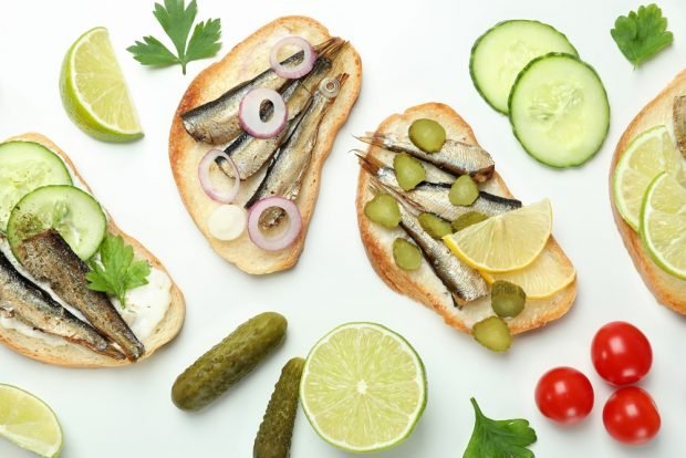 Sandwiches with sprats and pickled cucumber on a loaf