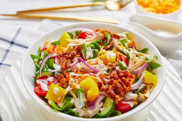 Meat salad with vegetables, cheese and fried bacon