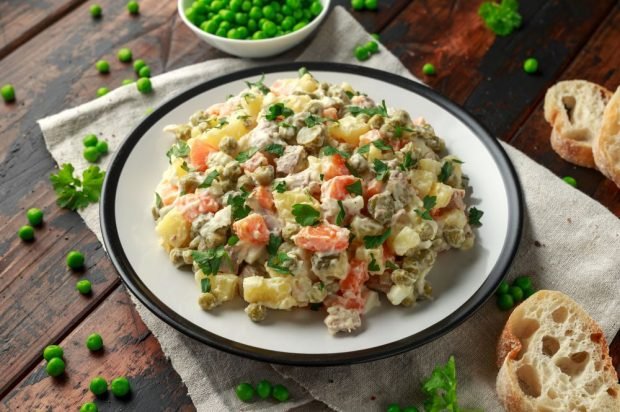 Meat salad with pickled cucumbers, green peas and boiled vegetables