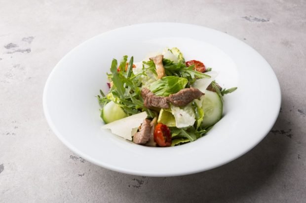 Salad with meat, dried tomatoes, cucumbers and parmesan