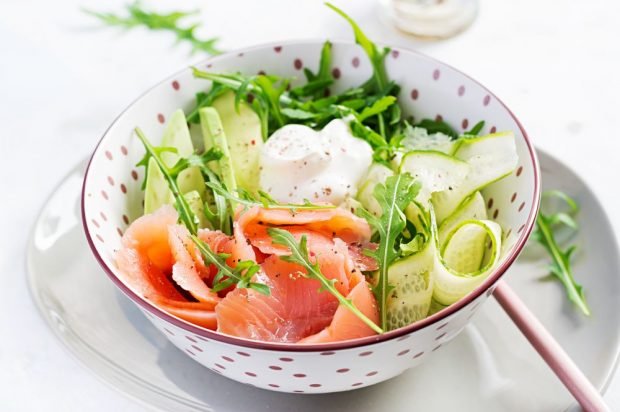 Delicious salad of cucumbers, avocado, red fish and arugula 