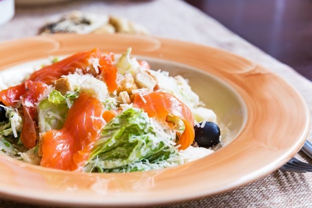 Caesar salad with red fish and olives 