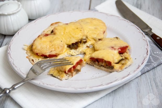 Chicken chops with mushrooms, tomatoes and cheese in the oven