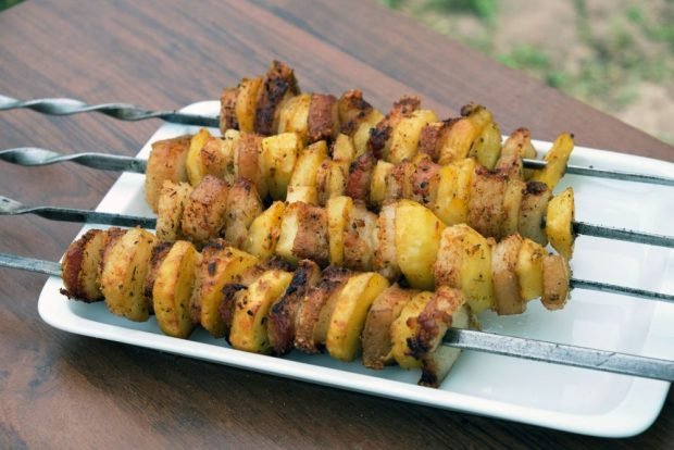 Potatoes with bacon on skewers on the grill