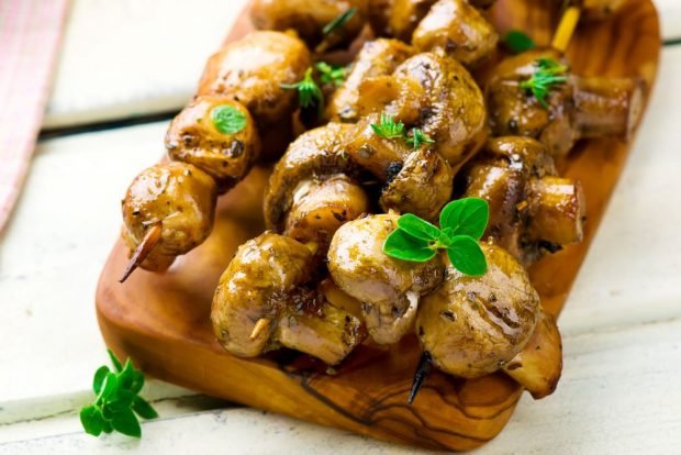 Shish kebab of champignons with mayonnaise on the grill 