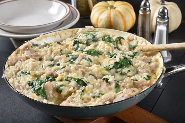 Rice casserole with chicken and spinach in a frying pan