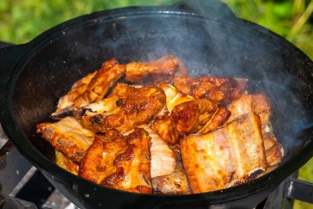 Pork ribs in a cauldron on a fire