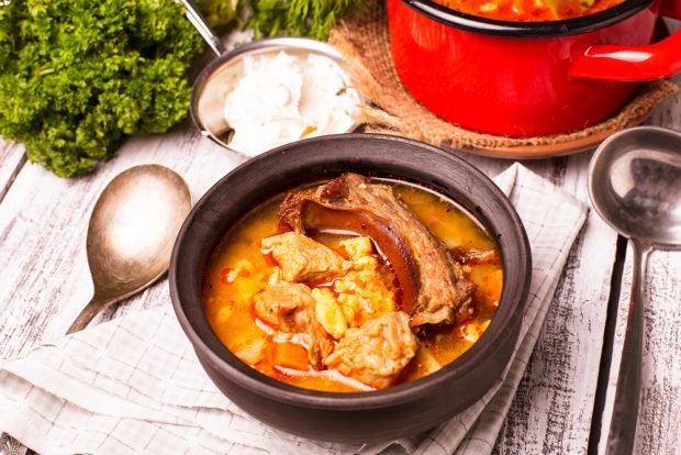 Pork ribs with vegetables in a cauldron on a campfire 