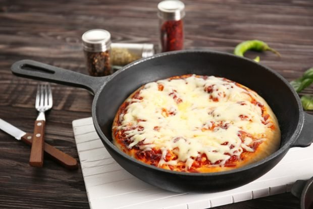 Homemade pizza with cheese in a frying pan