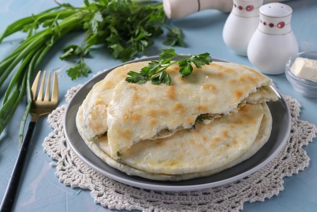 Khachapuri with cheese and green onions in a frying pan 